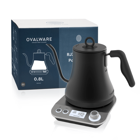 A black Magic Hour Electric Pour Over Kettle with a gooseneck spout is displayed on a built-in base with a digital screen and control dial, perfect for brewing loose leaf tea. The kettle packaging, showing a similar image and branding, is positioned behind the kettle. The text on the packaging reads "Magic Hour.