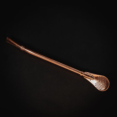 The Sips Tea Straw & Strainer Bombilla Case Packs by Alibaba are showcased against a black background. The bombilla features a straight shaft and a spoon-like filter end with small perforations, making it ideal for straining loose tea or yerba mate.