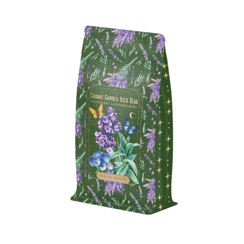 A green, floral-themed bag of Blueberry Lavender Mint: Cosmic Garden Iced Tea by Magic Hour. The packaging features illustrations of blueberries, lavender, butterflies, and stars, with the flavors listed as blackberry, lavender, and mint. Enjoy this delightful loose leaf tea blend for an organic tea experience.