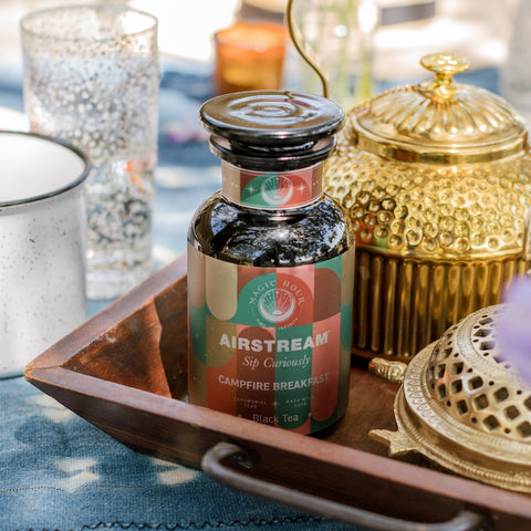 Close up of a Campfire Breakfast Violet Glass Apothecary Jar with gold teapot in the background