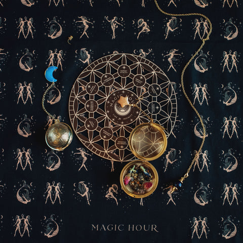 A circular astrological chart with phases of the moon, symbols, a small bowl filled with colorful gemstones, a metallic pendant, and a crescent moon decoration are laid on a fabric with an intricate starry pattern. "Crystal Grid: Flower of Life Tea Ceremony Altar" by Alibaba is written at the bottom, hinting at an event fueled by organic tea rituals.