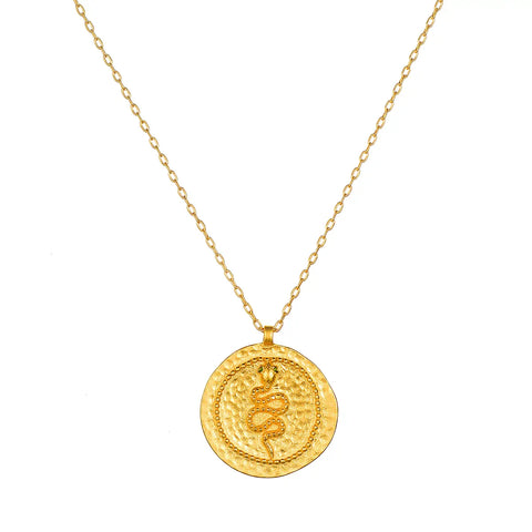 The Emerald Snake Coin Pendant Necklace is crafted from 18kt gold and features a delicate chain paired with a round coin pendant. The centerpiece of the pendant is an intricately engraved coiled serpent symbol, surrounded by fine, detailed patterns along the edges. It boasts a shiny, polished finish that enhances its elegant design.