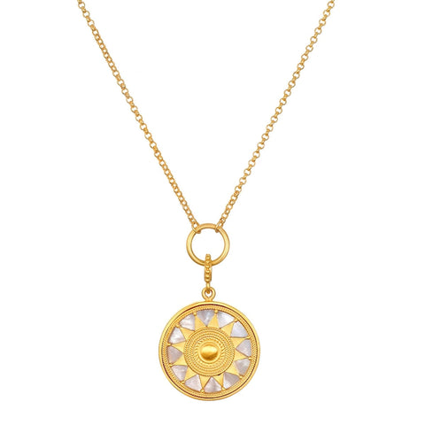 The Inward Journey Pearl Mandala Necklace showcases a circular mandala pendant featuring a sun design, embellished with alternating gold and pearl-like segments forming the sun's rays. This spiritual jewelry piece is suspended from a delicate 18KT gold plated chain, connected by a ring to the pendant.