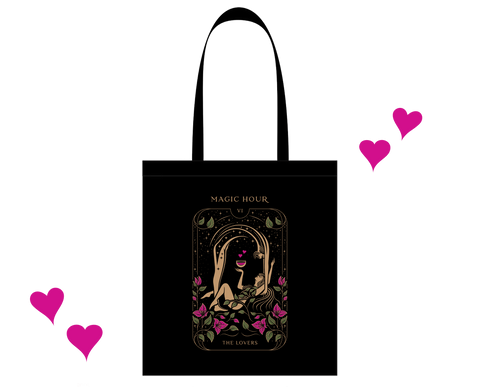 Introducing "The Lovers Tote Bag" – a black cotton tote bag adorned with a central design featuring a man and woman encircled by pink roses, all under a golden arch. The text "MAGIC HOUR" is proudly displayed above the design, while "THE LOVERS" graces the space below, echoing the essence of the Lovers Tarot Card. Delicate pink hearts float around the bag, adding an extra touch of magic.