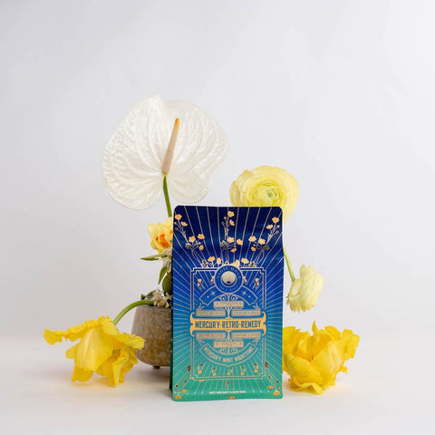 A vibrant card with the text "Mercury Mint Nighttime" is displayed against a pristine white background. It is surrounded by bright yellow and white flowers in a minimalist vase, enhanced by the soothing presence of lavender, adding a touch of natural beauty to the scene.