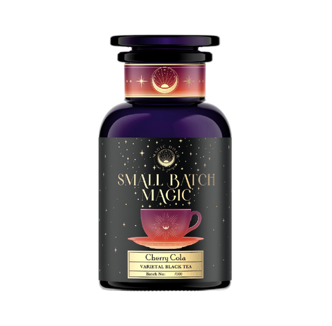 A dark purple jar with a black label reading "Magic Hour" and "Vanilla Cream Soda" with a batch number. The label also features a purple teacup on a saucer, surrounded by stars and cosmic imagery.