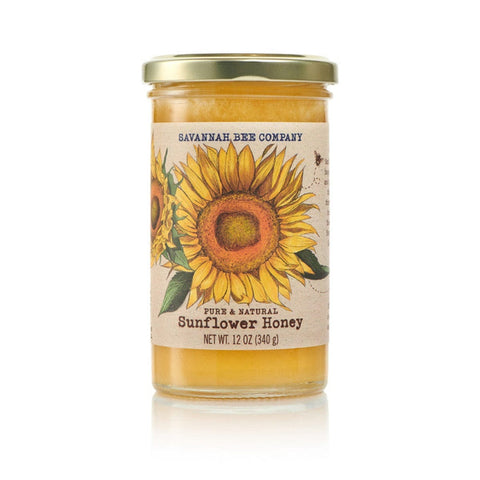 A 12-ounce glass jar of Savannah Bee Co. Honey - Sunflower, featuring a gold lid and a label with a prominent sunflower illustration. The label indicates the net weight as 340 grams, emphasizing its pure and natural sunflower honey sourced from Ukraine and Romania.