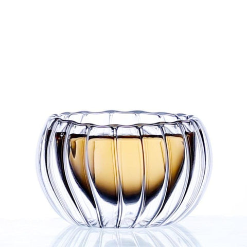 A transparent, ribbed glass bowl featuring a golden hue at the base, embodies an elegant and modern design similar to the Double-Walled Rippled Tea Cup. The empty bowl is displayed against a plain, white background, emphasizing its reflective and intricate texture.